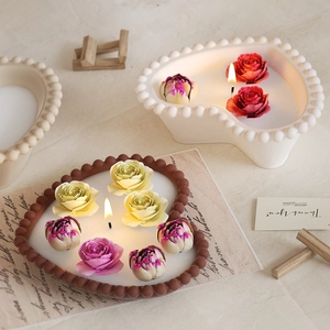 Detail of heart-shaped pearl candle holder with blooming rose and peony scented candles