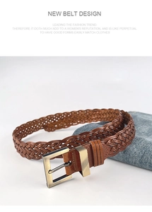Detail of brown braided leather belt with bronze metal buckle on denim jeans