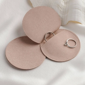 Macro detail of pink microfiber jewelry pouch showing three ring compartments on silk