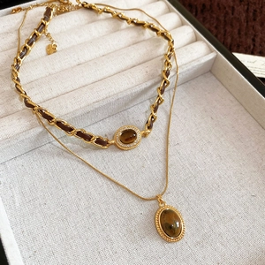 Dettaglio della collana a strati in oro 18k con ciondoli occhio di tigre e catena in pelle