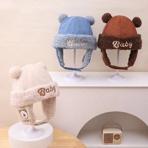 Detailed view of plush baby winter aviator hats with bear embroidery and fur pom-poms