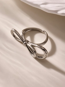 Macro view of a silver bow-shaped open ring with a polished mirror finish on a soft background