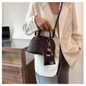 Detail of dark brown crocodile pattern shell bag with small matching pouch on model