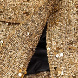 Giacca elegante in tweed con paillettes oro e nero e occhielli metallici di lusso