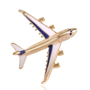 Detailed view of a gold aircraft brooch with blue and white enamel on a white background