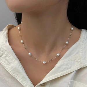 Close-up of minimalist freshwater pearl necklace on model with fine silver chain