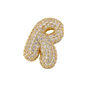 Macro view of gold plated pendant letter R fully encrusted with shimmering cubic zirconia
