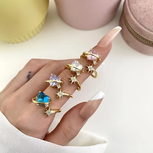 Detailed close-up of heart-shaped zircon rings with planetary rings on a model hand
