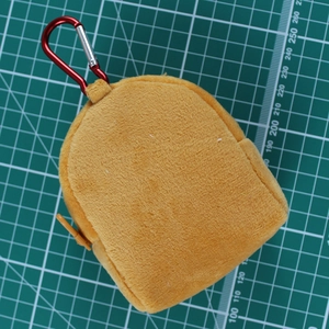 Brown Capybara plush mini storage bag with red carabiner clip on green grid mat