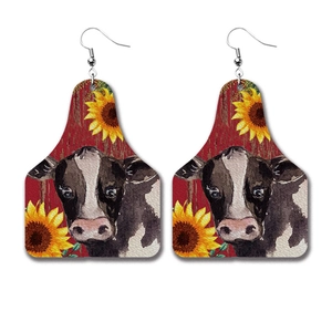 Cow head tag earrings with sunflower and dairy cow pattern on red faux leather background