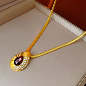 Detail of vintage gold snake chain necklace featuring a ruby red teardrop pendant