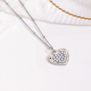 Macro detail of silver heart pendant with faux pearl inlays and irregular metal texture
