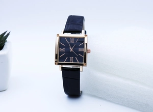 Detail view of square gold watch case with black dial and embossed leather strap