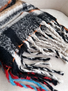 Close-up of thick plaid scarf with colorful fringe and soft woolen texture