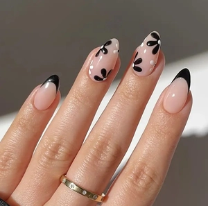 Detail of almond-shaped nails with nude base, black French tips and floral patterns