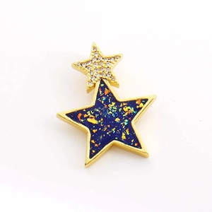Détail macro d'un pendentif double étoile doré avec paillettes bleues et zircon blanc