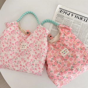Detailed view of quilted floral canvas handbag with snap button and light blue handles