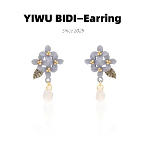 Detailed view of floral drop earrings with purple petals and a gold leaf pendant