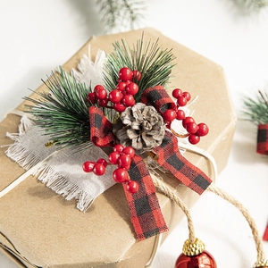 Christmas gift box decor with pine cones, red berries, and plaid bow on kraft paper
