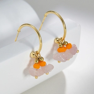 Detail of 14k gold-plated C-shaped earrings with orange beads and pink stone pendants