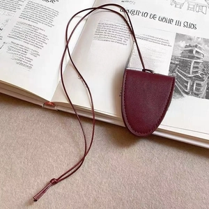 Brillenhalter-Halskette aus weinrotem Leder auf einem Magazin und einem Holztisch