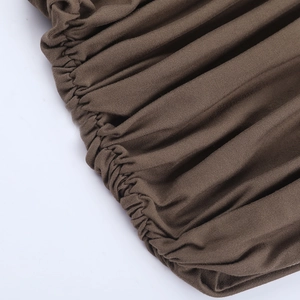 Macro shot of dark brown ruched fabric showing elastic stitching on high-stretch dress