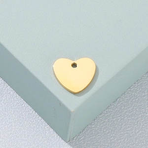 Polished heart shaped golden stainless steel pendant for necklace on minimalist background