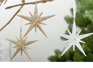 Champagne gold glitter star ornaments hanging on branches for festive Christmas decor