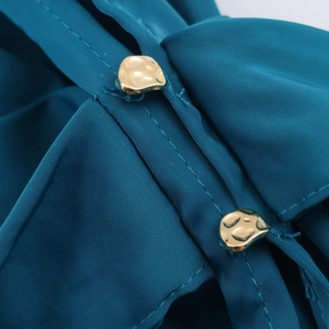 Détail du tissu satiné bleu canard avec deux boutons dorés et coutures de haute qualité