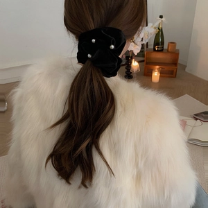 Close-up of velvet hair scrunchie with pearls worn by model in a soft indoor setting