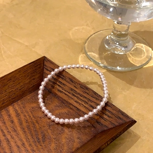 Gros plan d'un élégant bracelet de perles roses posé sur un plateau en bois
