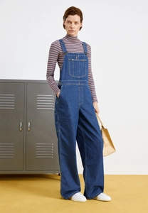 Detail of loose fit dark blue denim overalls with metal buckle and adjustable straps