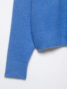Macro shot of azure blue knit cardigan featuring ribbed hem and soft wool blend texture