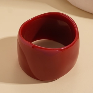 Macro shot of smooth dark red resin bracelet with polished finish and thick irregular curves