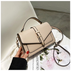Close-up of beige crossbody bag with adjustable strap and decorative metal buckle
