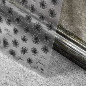 Detailed close-up of semi-transparent black floral nail stickers with fine line art
