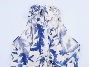 Détail d'une robe dos nu bleue et blanche avec bordure en dentelle et nœud au dos