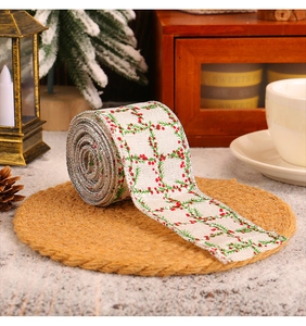 Close-up of beige Christmas ribbon with red berry patterns and silver glitter edges