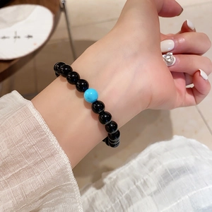 Close-up of beaded bracelet with black onyx and turquoise stone on woman's wrist