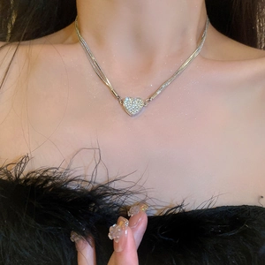 Detailed view of layered silver heart necklace with pavé zircons worn by a model