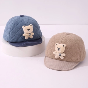 Close-up of quilted velvet baby caps with plush bear detail and corduroy brim