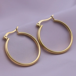 Macro view of 18K gold plated hoop earrings with latch-back closure on purple fabric