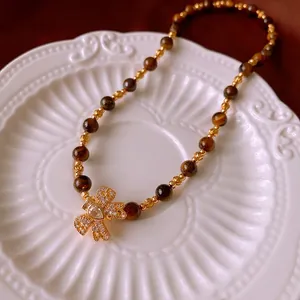 Tiger eye stone bead necklace with a gold bow pendant and sparkling zircon stones
