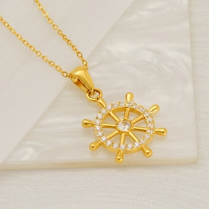 Minimalist gold rudder compass pendant necklace with white zircons on marble surface