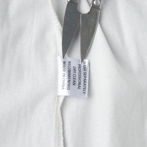 Gros plan détaillé de l'étiquette d'entretien sur l'ensemble robe en coton blanc