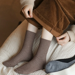 Close-up of rib-knit wool socks texture showing the brownish-grey fabric and high elasticity