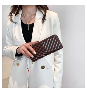Détail d'un portefeuille en cuir verni matelassé marron foncé tenu par un mannequin