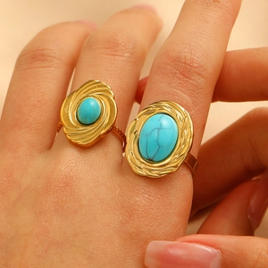 Close-up of gold-plated open rings with turquoise stones and braided metal textures