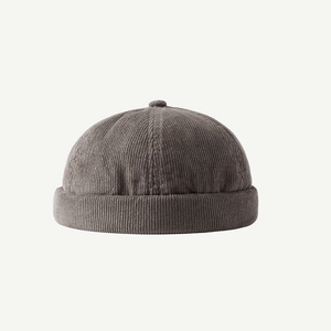 Detailed view of the dark grey corduroy fabric texture and crown button on the brimless cap