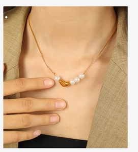 Gros plan détaillé d'un collier pendentif cœur doré avec perles blanches sur un mannequin